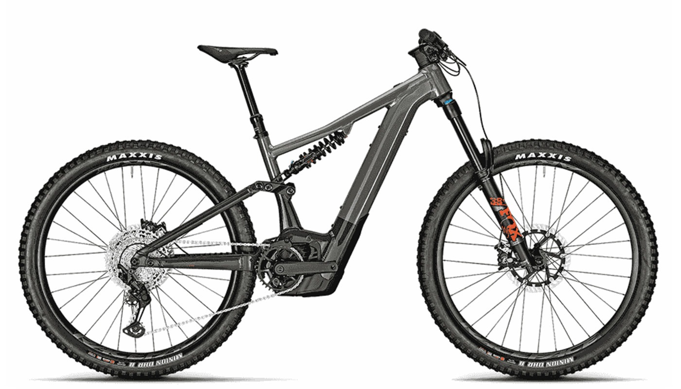 Ein vollgefedertes E-MTB in Titansilber mit einem markanten Stahlfederdämpfer im Rahmen, Maxxis-Reifen und orangefarbenen Fox-Gabel-Decals.