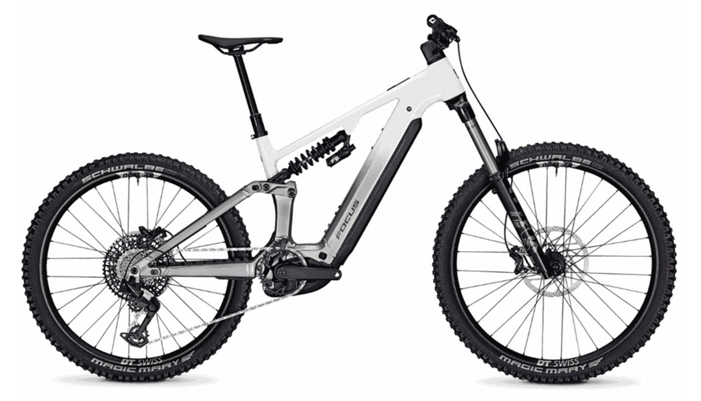 Ein vollgefedertes Focus E-Mountainbike mit einem weiß-grau verlaufenden Rahmen, einem Stahlfederdämpfer und groben Schwalbe Magic Mary-Reifen.